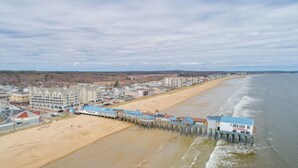 A coastal hotel with a pier extending into the ocean, featuring multiple buildings and a sandy beach.