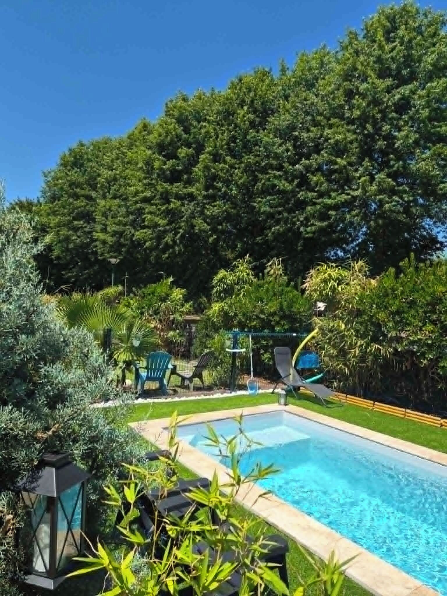 Ein Swimmingpool mit umlaufendem Garten, einem Pavillon und blauem Himmel.