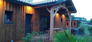 A wooden cabin with a covered patio, a dining area, and a small garden. - Les Bord'Océanes Villa Marensine **** with a pool, sauna, and private spa (Vielle-Saint-Girons)