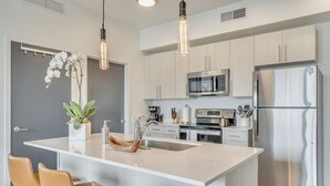 A modern kitchen with a central island, stainless steel appliances, and pendant lighting. - LCF - Downtown SLC - 1BR/1BA - CoWork + Gym - Near Delta Center - Garage (Salt Lake City)