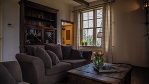 A cozy living room with a dark brown sofa, a wooden coffee table, and a window with curtains.