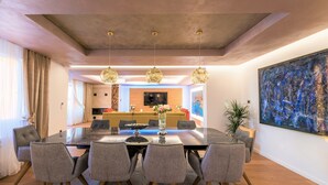 A modern dining area with a glass table, grey upholstered chairs, and a vase of flowers.
