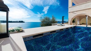 A swimming pool with a clear view of the sea and distant land.