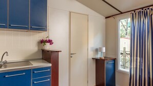 A compact kitchen with blue cabinets, a wooden countertop, and a small sink. - Comfort Lodge Maremma (Grosseto)