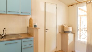 Une cuisine de taille réduite avec des meubles de couleur bleu clair, un évier et une fenêtre donnant sur un paysage agréable.