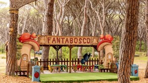 Une maison de jeu en bois, surmontée d’une enseigne portant l’inscription « FANTABOSCO », entourée d’arbres.