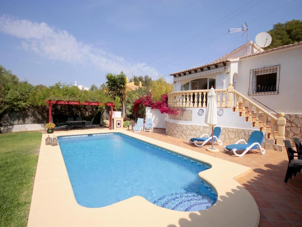 A swimming pool with a red pergola, lounge chairs, and a staircase leading to a balcony.