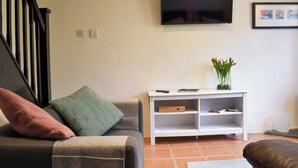 A living room with a sofa, a white entertainment unit, a flat-screen TV, and a framed picture on the wall. - 2 bedroom accommodation in Washfield, near Tiverton (Washfield, near Tiverton)