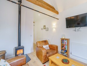 A cozy living room with a fireplace, leather sofa, wooden coffee table, and a bookshelf.