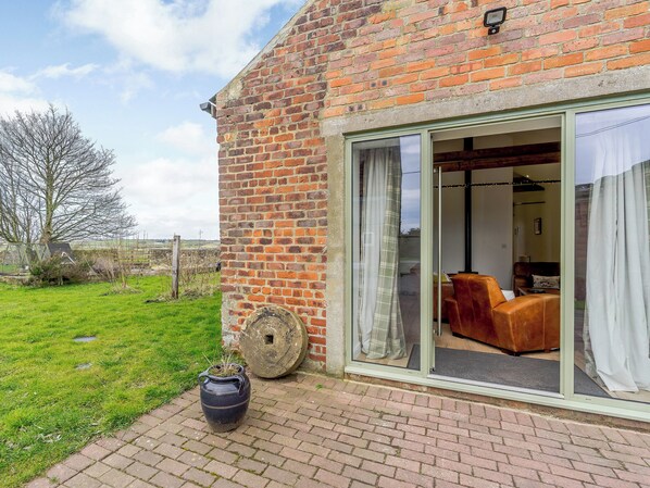 A brick building with a sliding glass door leading to a living room with a sofa and a coffee table.