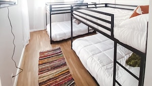 Un dormitorio con literas, un ventilador de techo y una alfombra a rayas.