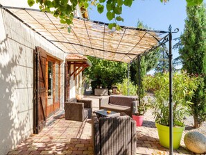 A patio with wicker furniture and a pergola, surrounded by potted plants and a brick floor. - Countryside holiday home with pool (RENAISON)