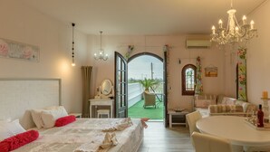 Une chambre d’hôtel avec un lit, une table à manger, un lustre et une vue sur l’extérieur.