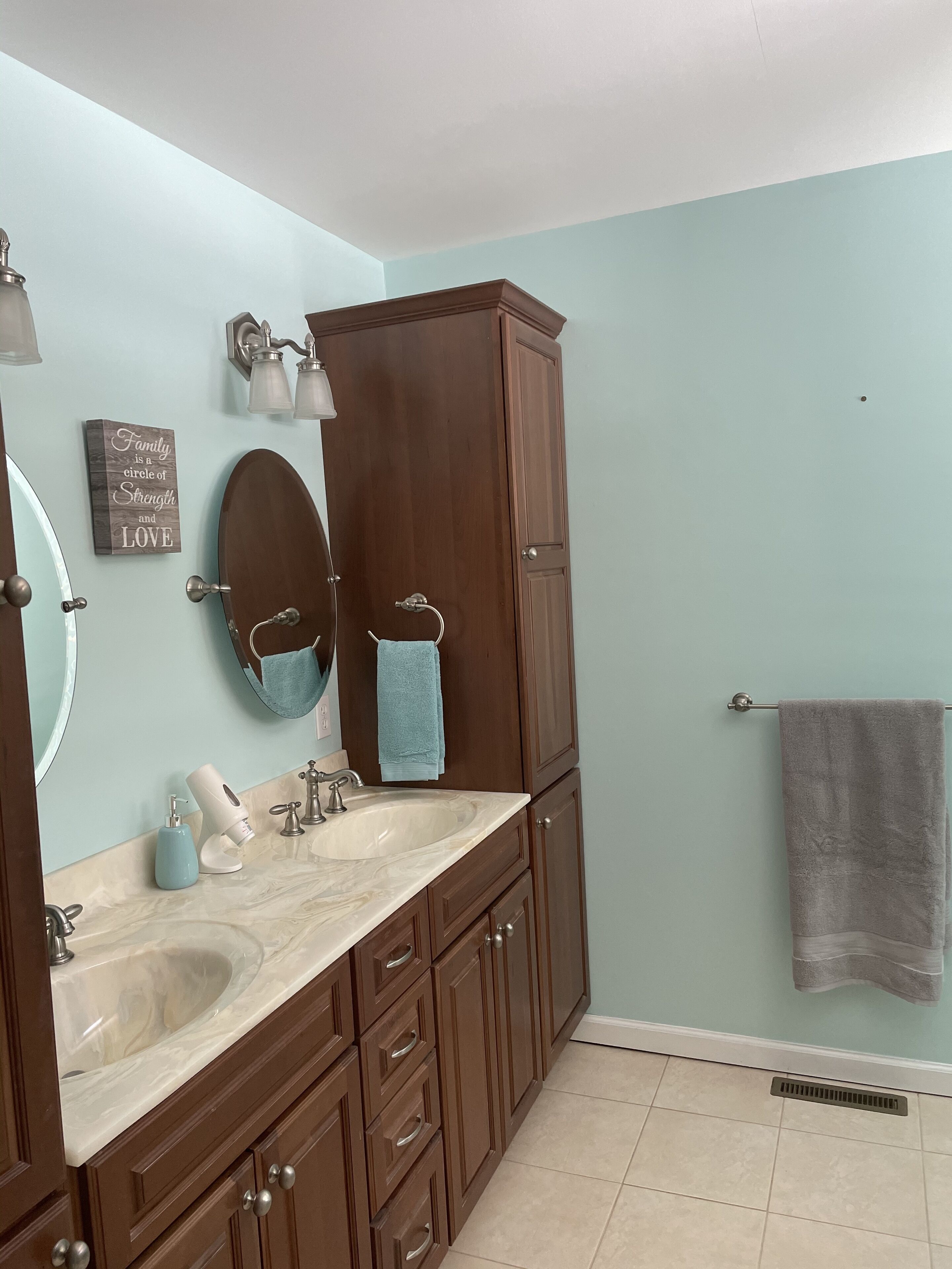A bathroom with two sinks, a large mirror, wooden cabinets, and a towel rack.