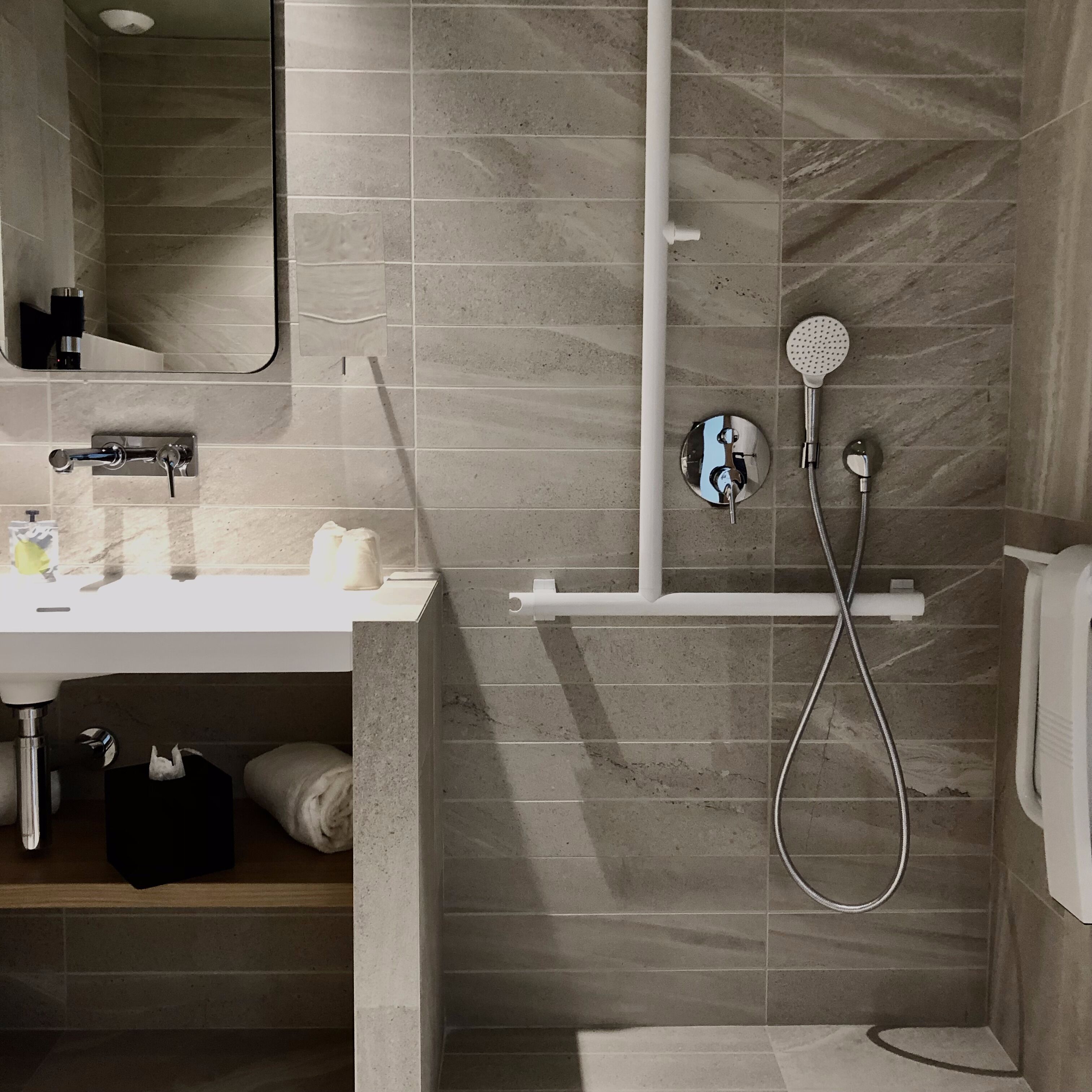 A modern bathroom with a shower, a sink, and a mirror.