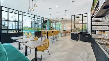 A modern restaurant with high ceilings, pendant lighting, and a mix of yellow and green seating.