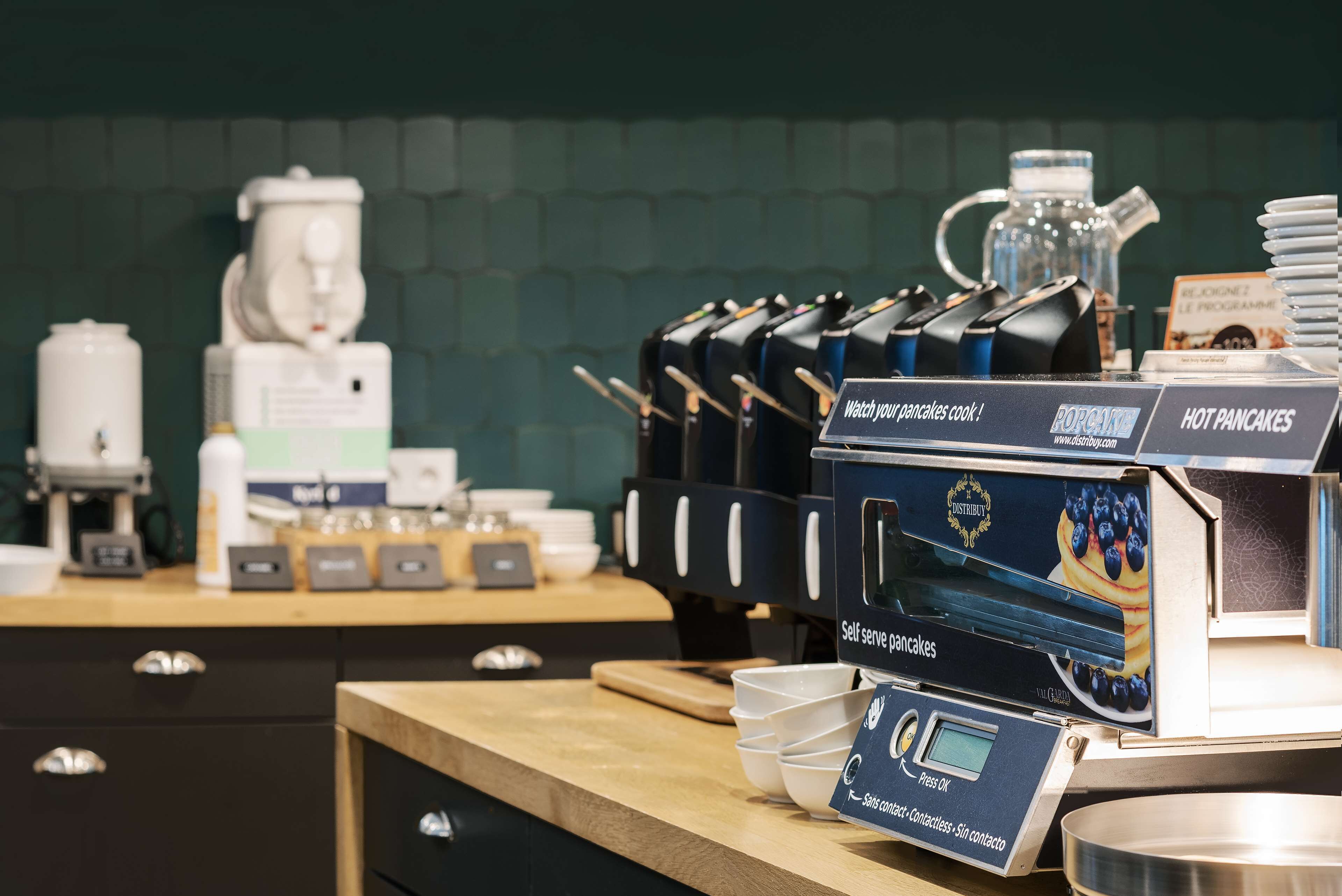 Uma estação de panquecas de serviço livre com um visor digital, uma máquina de café e um dispensador de água.