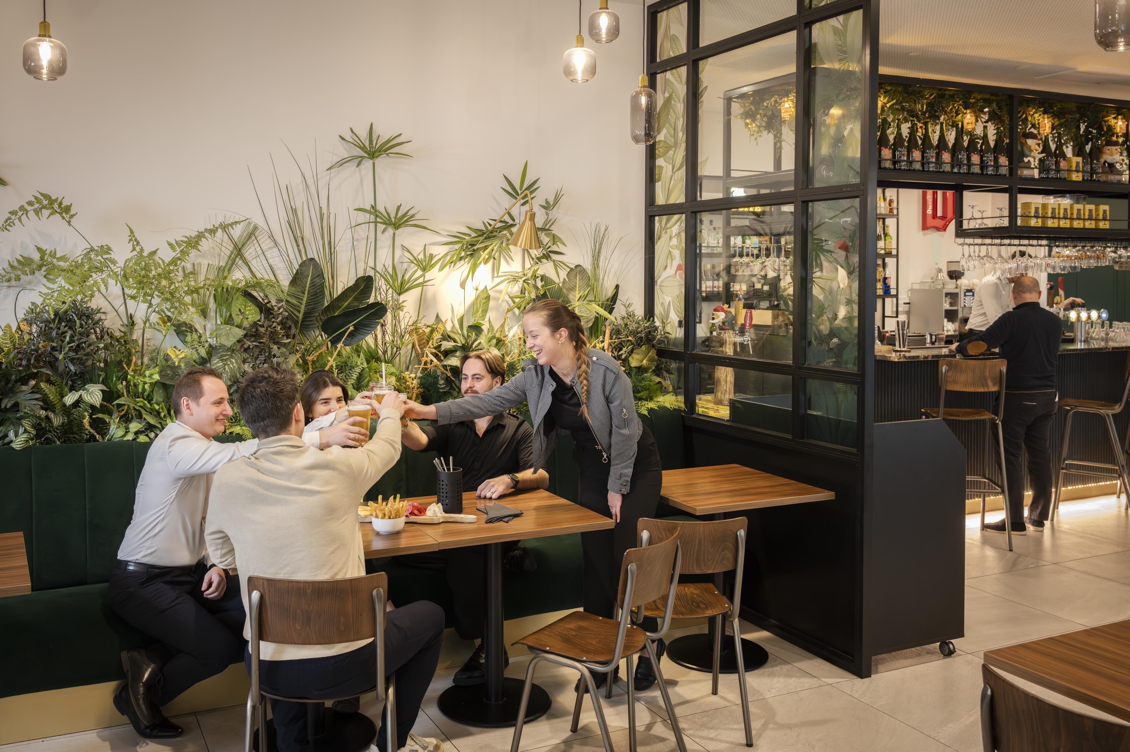 A restaurant with a bar area, indoor plants, and a modern interior design.