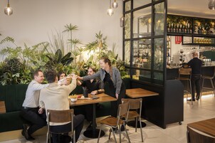 Un restaurante con zona de bar, plantas de interior y diseño de interiores moderno.
