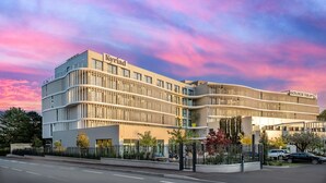 Un hotel moderno con facciata curva, diversi piani e un cartello ben visibile.