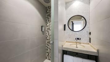 A modern bathroom with a shower, a sink with a mirror, and a towel rack.