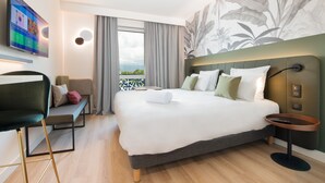 Een moderne hotelkamer met een groot bed, een bureau met stoel, een televisie en een balkon met uitzicht.