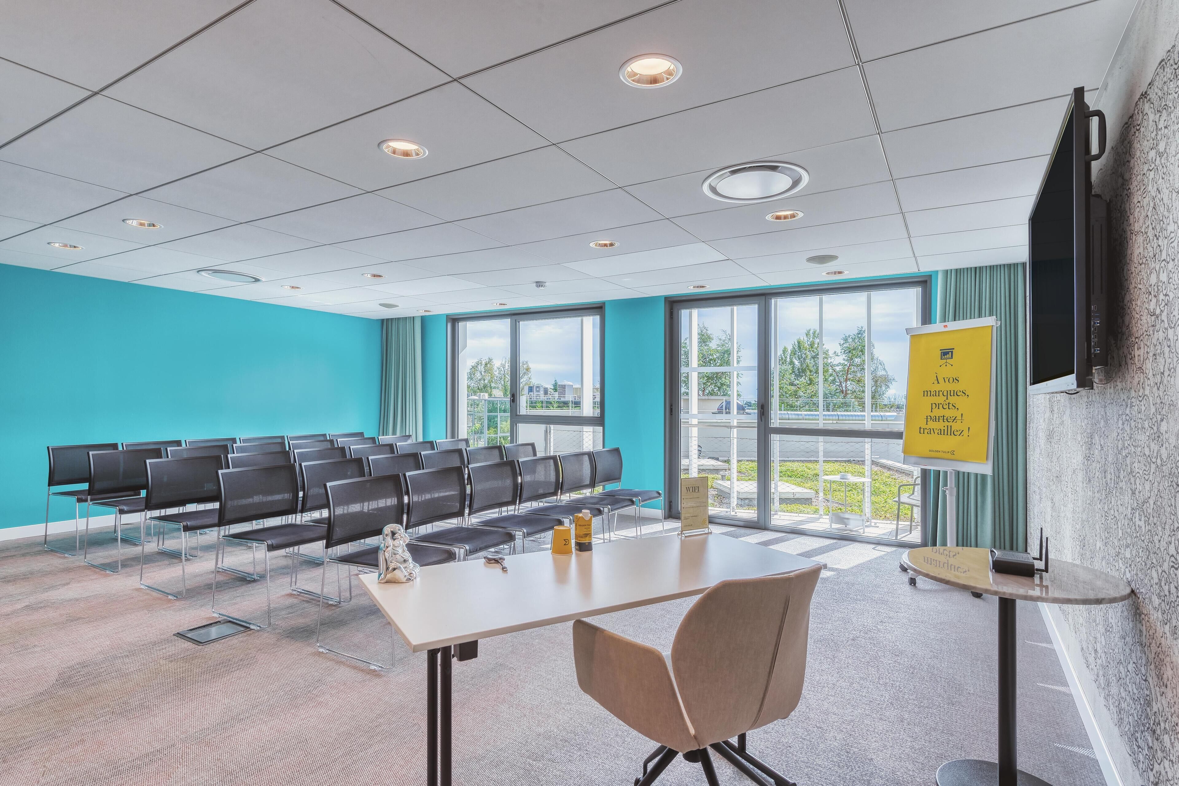 A conference room with a long table, chairs, and a projector screen.