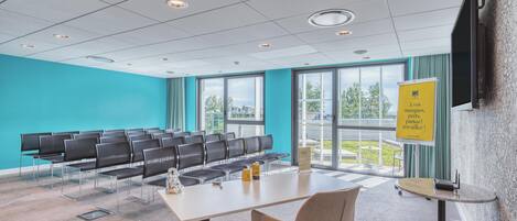 A conference room with a long table, chairs, and a projector screen.