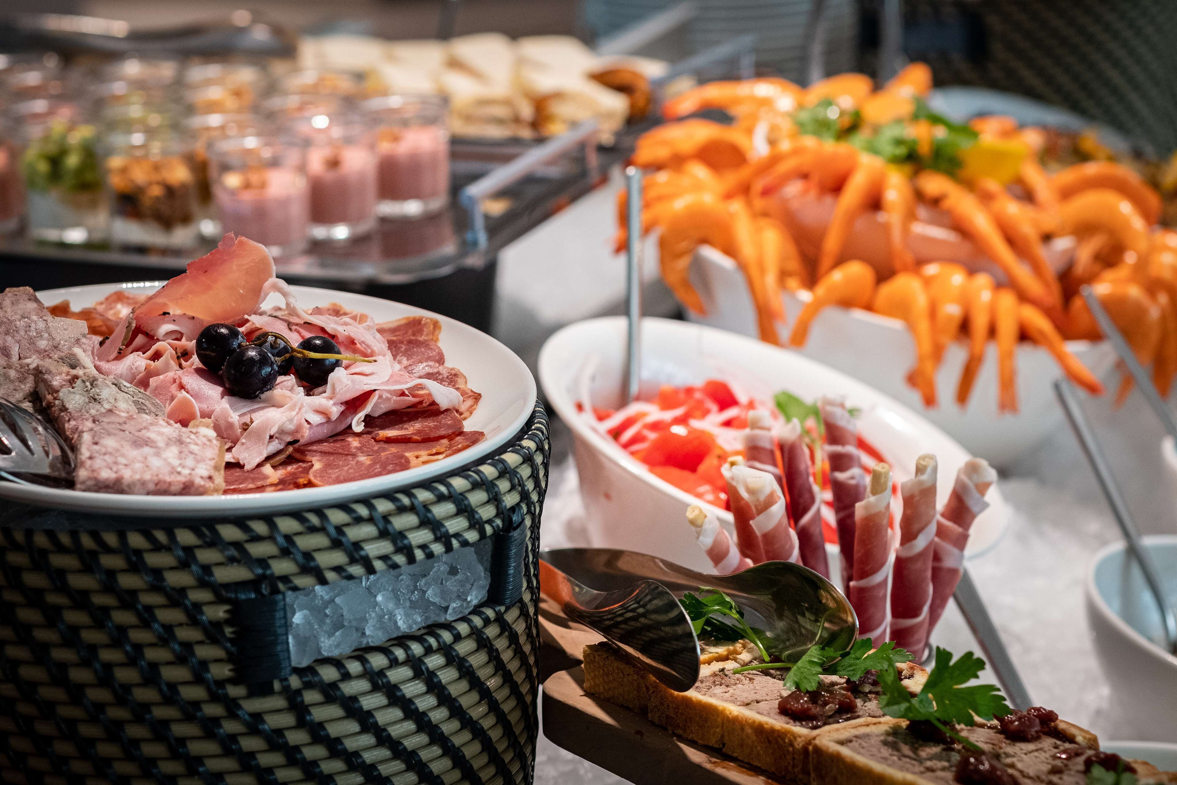 Een buffet met diverse gerechten, waaronder vleeswaren, kazen en garneringen.
