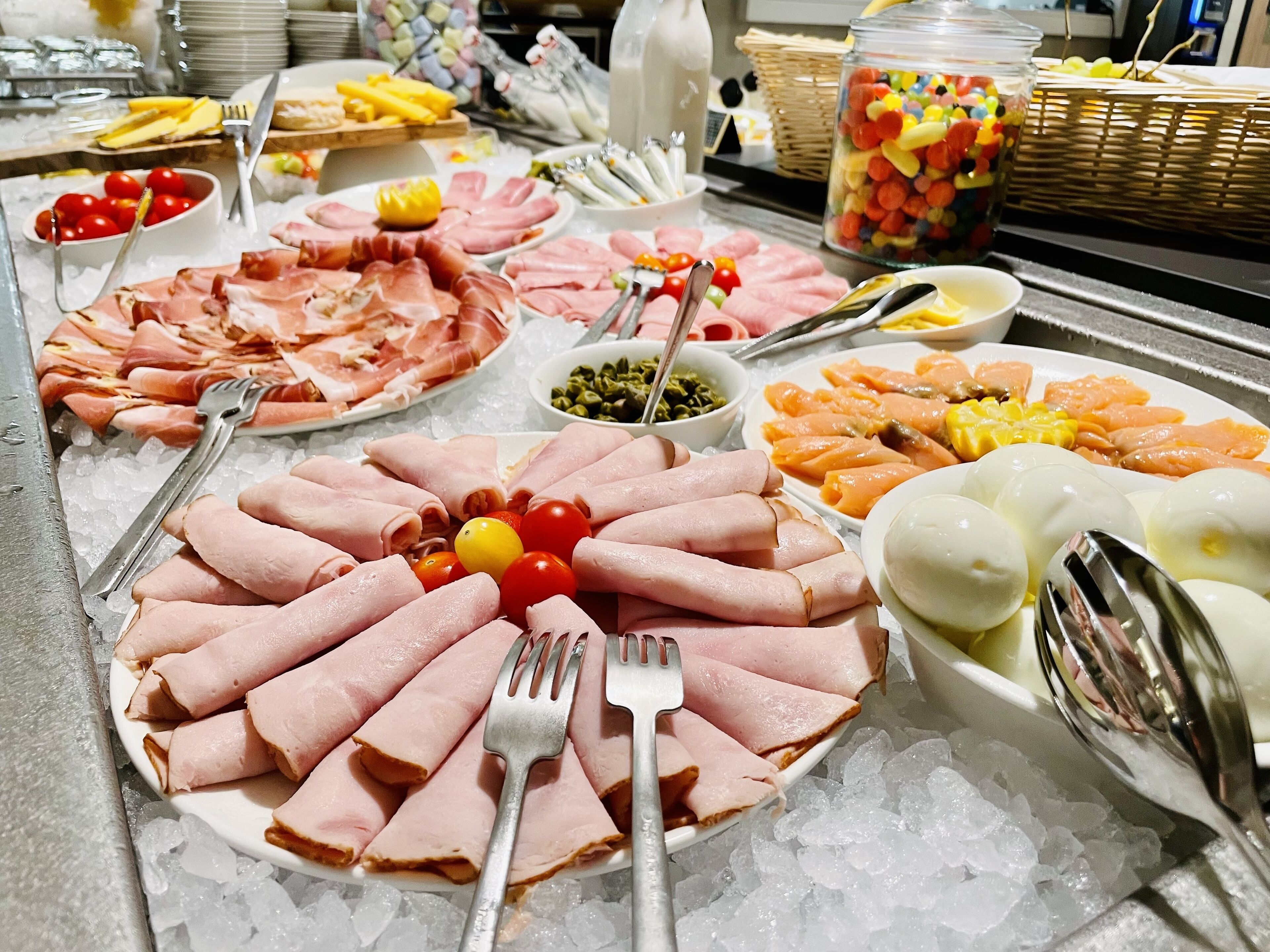 Ein Buffet mit verschiedenen Speisen, darunter Aufschnitt, Gemüse und Obst auf einer Eisplatte.