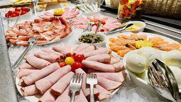Ein Buffet mit verschiedenen Speisen, darunter Aufschnitt, Gemüse und Obst auf einer Eisplatte.