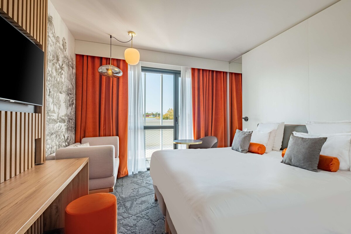 Une chambre d’hôtel moderne équipée d’un grand lit, d’un bureau, d’une chaise et d’un téléviseur.
