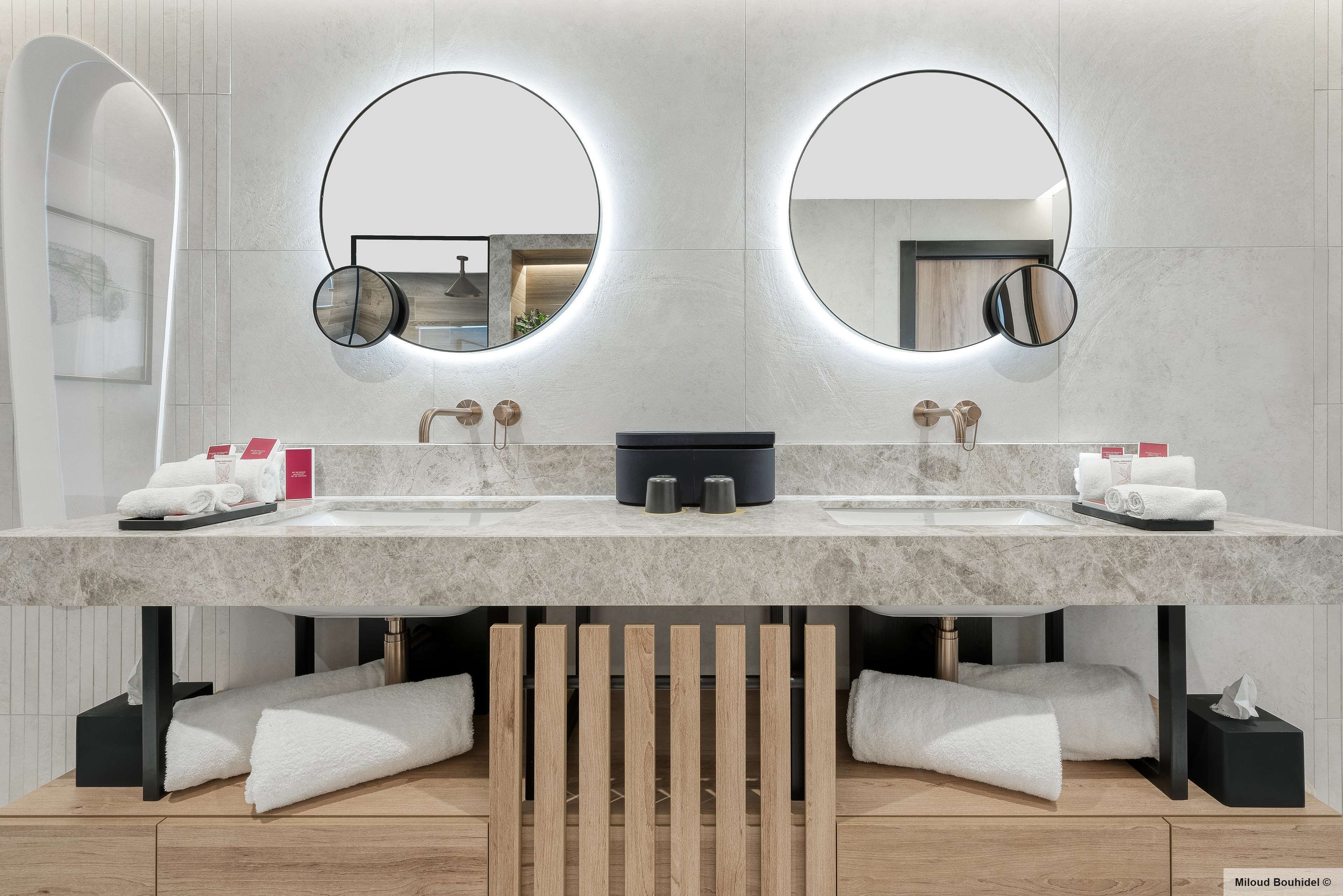 Une salle de bain moderne avec deux lavabos, de grands miroirs et un meuble-lavabo en bois.