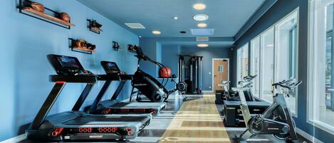 Un gimnasio con cintas de correr, bicicletas estáticas y máquinas de pesas.