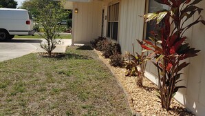 A single-story house with a front porch, a driveway, and a small garden with various plants. - Split 2 bdrm/2 full bath floorplan, All new appliances, yearly rental (Stuart)