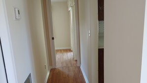 A hallway with wooden flooring, white walls, and a door leading to another room. - Split 2 bdrm/2 full bath floorplan, All new appliances, yearly rental (Stuart)