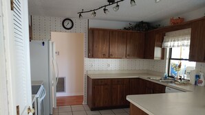 A kitchen with wooden cabinets, a white countertop, a built-in oven, and a clock on the wall. - Split 2 bdrm/2 full bath floorplan, All new appliances, yearly rental (Stuart)
