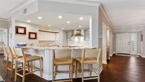 A kitchen with a central island, white cabinetry, and a stainless steel range hood. - 5508 Hampton Place - UPDATED Villa with Fantastic Oceanfront Views! (Hilton Head Island)