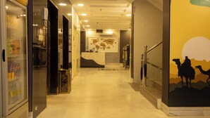 A hotel corridor with a reception desk, a refrigerator with beverages, and a wall with a map and a camel illustration. -  Areen Alnaeem Hotel (Jeddah)