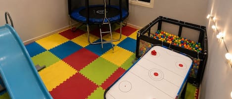 Una sala giochi con un trampolino, un tavolo da calcio e una piscina di palline.