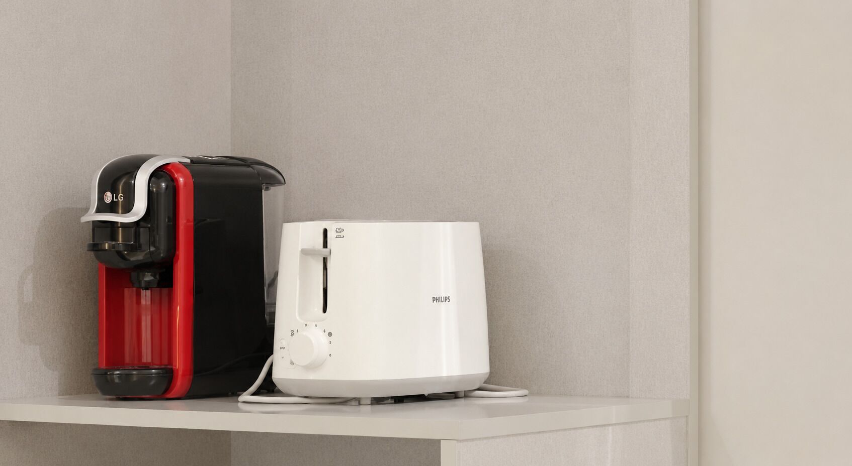Una macchina da caffè e un elettrodomestico bianco su uno scaffale bianco, su uno sfondo neutro.