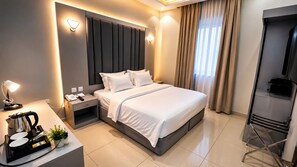 A modern hotel room with a large bed, bedside tables, a desk with a lamp, and a coffee maker. -  Areen Alnaeem Hotel (Jeddah)