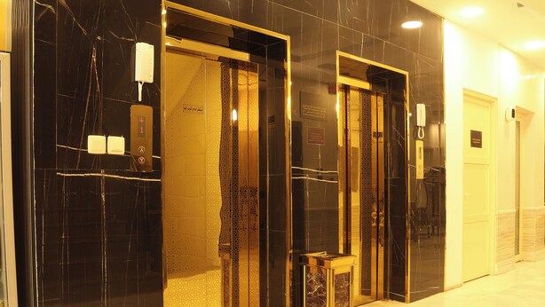 A hotel lobby with marble flooring, a reception desk, and a glass elevator. -  Areen Alnaeem Hotel (Jeddah)