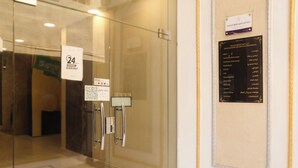 A hotel entrance with a glass door, a sign indicating 24-hour service, and a list of amenities including a lounge, utility services, and laundry. -  Areen Alnaeem Hotel (Jeddah)