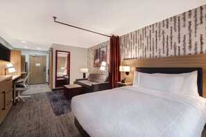 Una habitació d'hotel amb un llit gran, un escriptori, una cadira, una taula petita i una televisió.