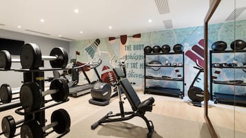 A gym with weightlifting equipment, treadmills, and a wall with motivational text.
