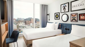 A hotel room with two beds, a desk, and a chair. There are framed pictures on the wall, including one with the word "DREAMS" and another with a monkey. - Hampton by Hilton Dublin City Centre (Dublin)