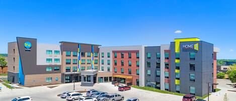 A modern hotel with multiple buildings, a parking lot, and a clear blue sky.