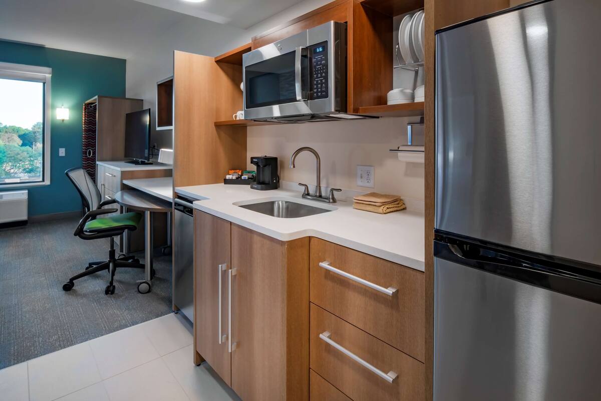 A modern kitchen with stainless steel appliances, wooden cabinets, and a built-in microwave.
