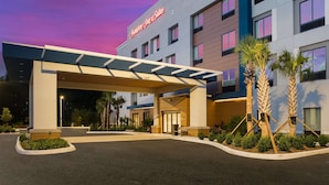 A hotel entrance with a clearway of 13.6 feet, palm trees, and a modern building facade. - Hampton Inn & Suites Ruskin I-75 (Ruskin)